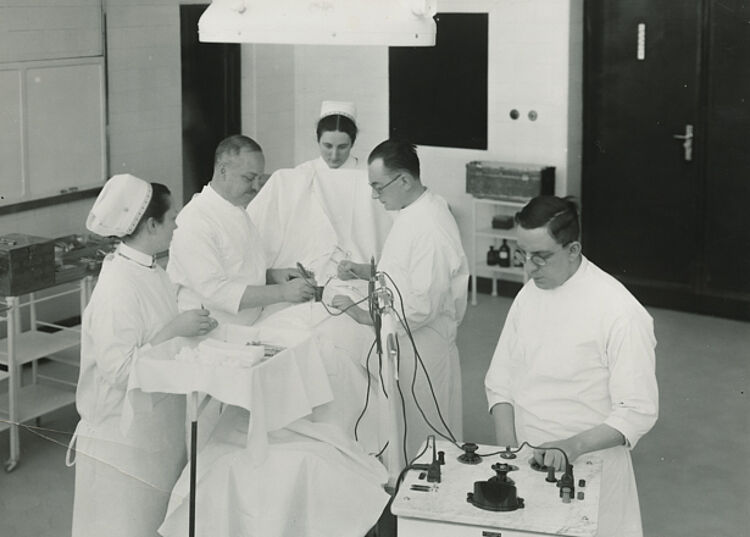 Emil Heymann bei einer Hirnoperation mit dem von ihm konzipierten Hochfrequenzgerät im Augusta-Hospital, um 1930 (Gerhard Heymann / DRK) Emil Heymann bei einer Hirnoperation mit dem von ihm konzipierten Hochfrequenzgerät im Augusta-Hospital, um 1930 (Gerhard Heymann / DRK)